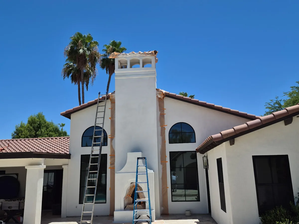 Extension ladder leaning against a two story Spanish style home during exterior work